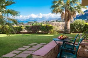 a table with a bowl of fruit and a palm tree at Dia Apartments in Hersonissos