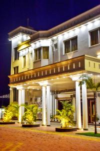 a large white building with palm trees in front of it at GOLDEN GLEAM RESORTS in Ingrāj Bāzār