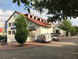 a large white building with cars parked in front of it at Engelhard Das Landhotel Garni in Kirchheim am Ries