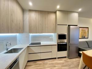 kuchnia z białymi szafkami i lodówką ze stali nierdzewnej w obiekcie Delight Apartment w Tiranie