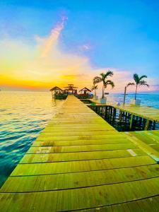 a wooden pier in the water with palm trees at Ocean house karimunjawa in Karimunjawa