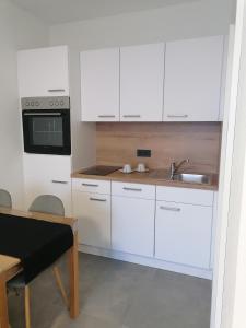 een keuken met witte kasten en een wastafel bij Schöne gemütliche Wohnung, Ferienwohnung in ruhiger Lage in Auerbach