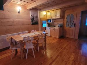a kitchen and dining room with a wooden table and chairs at Domek u Beaty in Dzianisz