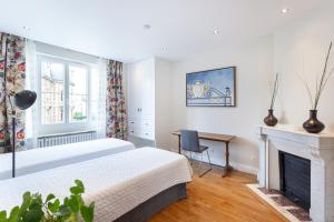 a bedroom with two beds and a fireplace at Les appartements de Chantilly - gare in Chantilly