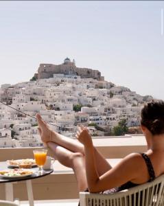 a woman sitting on a chair in front of a building at Anatoli Luxury Studios & Suites in Astypalaia