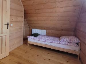 um pequeno quarto com uma cama num chalé de madeira em Domek u Beaty em Dzianisz