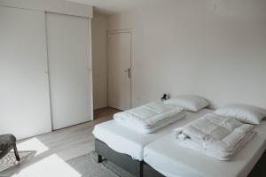 een witte slaapkamer met 2 bedden en handdoeken bij Villa Bandi - Group & Family House in Lanaken