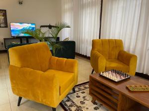 2 gelbe Stühle und ein Tisch im Wohnzimmer in der Unterkunft The Jewel and the Lake in Jinja