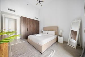 a bedroom with a large white bed and a mirror at Stylish 1BR Apt Umm Suqeim 3 in Dubai