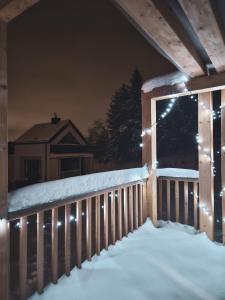 un porche cubierto de nieve por la noche con luces en Cienista Dolina 