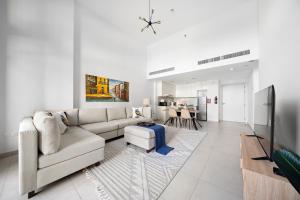 a living room with a white couch and a tv at Stylish 1BR Apt Umm Suqeim 3 in Dubai