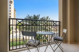 einen Balkon mit 2 Stühlen und einem Tisch auf dem Balkon in der Unterkunft Stylish 1BR Apt Umm Suqeim 3 in Dubai