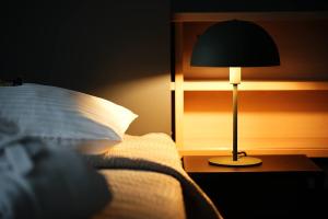 a lamp sitting on a table next to a bed at Hotel Navalis, Klaipėda in Klaipėda