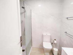y baño blanco con aseo y ducha. en Elegant apartment with private workspace, en Candelaria