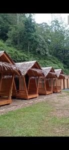 a row of wooden huts with trees in the background at Sultan Resort Syariah in Payakumbuh