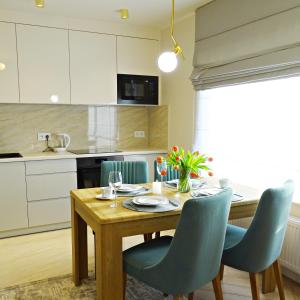 a kitchen with a wooden table and blue chairs at Apartamenty u ROXI in Jelenia Góra