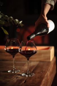 uma pessoa a derramar vinho em dois copos numa mesa em Moulin Renaudiots - Maison d'hôtes em Autun