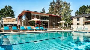 a swimming pool with blue chairs and umbrellas at Sharon Green apartments by FantasticStay in Menlo Park