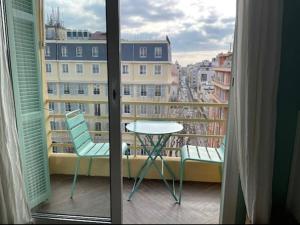 a balcony with a table and chairs and a window at Happy Home in Nice