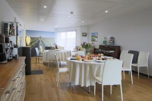 a dining room with a table and white chairs at Le Clos du Moulin in Vaudemanges