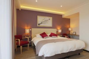 a bedroom with a large bed and red chairs at Le Clos du Moulin in Vaudemanges