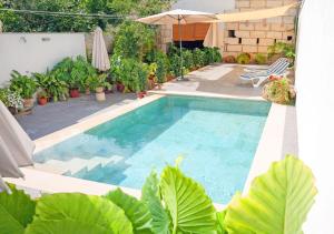 a swimming pool with plants and an umbrella at Can Peret - Sa Pobla in Sa Pobla