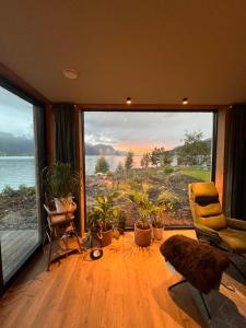 a room with a large window with a chair and plants at Modern house by the Fjord in Sandane, Nordfjord. in Sandane