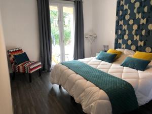 een slaapkamer met een groot bed en een stoel bij Le Mas Victoria - Chambres d'hôtes avec table d'hôtes in Carcassonne
