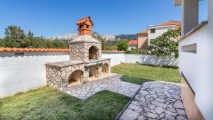 a stone fireplace in a yard next to a white wall at Charmantes Ferienhaus 200 Meter zum Strand in Baška