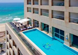 an overhead view of a hotel with a swimming pool and the beach at Sweet Love - דירה מהממת על הים עם נוף in Bat Yam