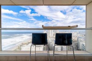 twee stoelen voor een groot raam met uitzicht op de oceaan bij Sweet Love - דירה מהממת על הים עם נוף in Bat Yam