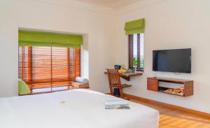 - une chambre avec un lit et une télévision à écran plat dans l'établissement Elites Riverside Hotel & Spa Hoi An, à Hội An