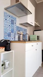 uma cozinha com armários brancos e uma parede de azulejos em Le Case di Ale em Salerno