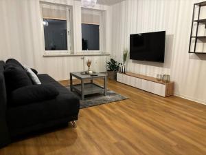 sala de estar con sofá negro y TV en FeWo Carl: Businessapartment mit Stil, en Bielefeld