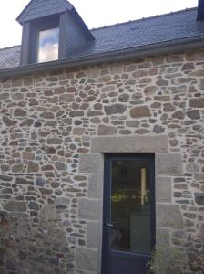 a stone building with a black door and a window at Charmant Appartement in Saint Malo