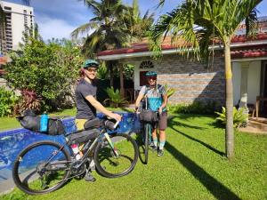 duas pessoas de pé com as suas bicicletas em frente a uma casa em Ocean Gate Negombo em Negombo