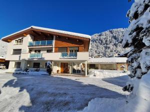 a house in the snow with a mountain in the background at Ferienwohnungen Pollhammer in Sankt Gallenkirch