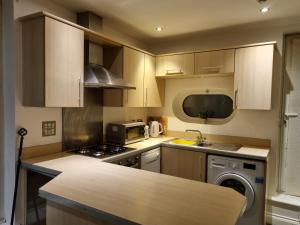 a kitchen with wooden cabinets and a washer and dryer at Stefo Maisonette Sleeps 6 in Leicester