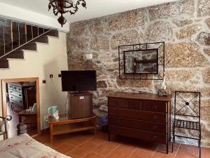 Quinta Do Moinho Turismo de Natureza في Aldeia Viçosa: غرفة نوم بجدار حجري مع تلفزيون وخزانة