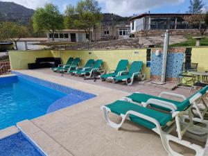 a row of lounge chairs next to a swimming pool at Quinta Do Moinho Turismo de Natureza in Aldeia Viçosa