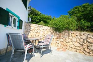 a patio with two chairs and a table and a stone wall at 100 Meter zur kristallklaren Adria in Baška
