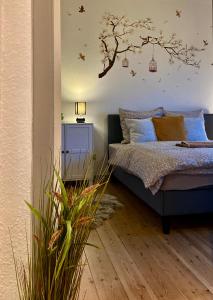 a bedroom with a bed with a tree on the wall at Dejlig 2 værelses lejlighed in Randers