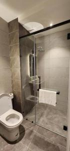 a bathroom with a toilet and a glass shower at Axon Serviced Suites in Kuala Lumpur