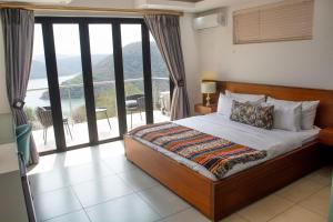 a bedroom with a bed with a view of a balcony at Impecto Guest House in Jozini