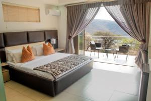 a bedroom with a bed and a balcony with a view at Impecto Guest House in Jozini