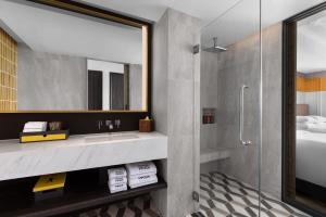 a bathroom with a shower and a sink and a mirror at Madi Paidi Bangkok, Autograph Collection in Bangkok