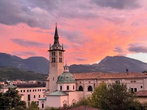 un edificio con una torre de reloj frente a la puesta de sol en Casetta alla fontana, en Villa Lagarina