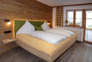 a large bed in a room with wooden walls at Gmeinder's Landhaus in Immenstadt im Allgäu
