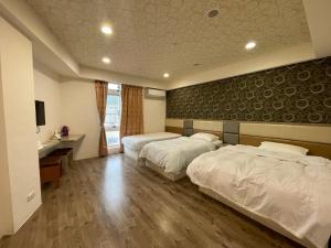 ein Hotelzimmer mit 2 Betten und einem Schreibtisch in der Unterkunft Dong Yong Travel in Dongyin/