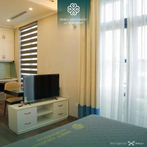 Chuỗi căn hộ Merci Apartment & Homestay - Vinhomes Imperia Hai Phong في هاي فونج: غرفة نوم مع تلفزيون على خزانة مع نافذة